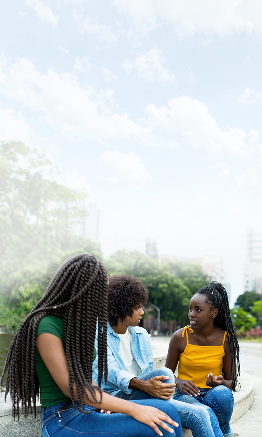 Three teenagers sitting on steps outside talking.